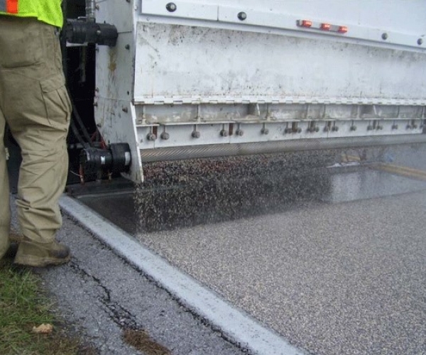 A machine layering a road with high friction surfacing.