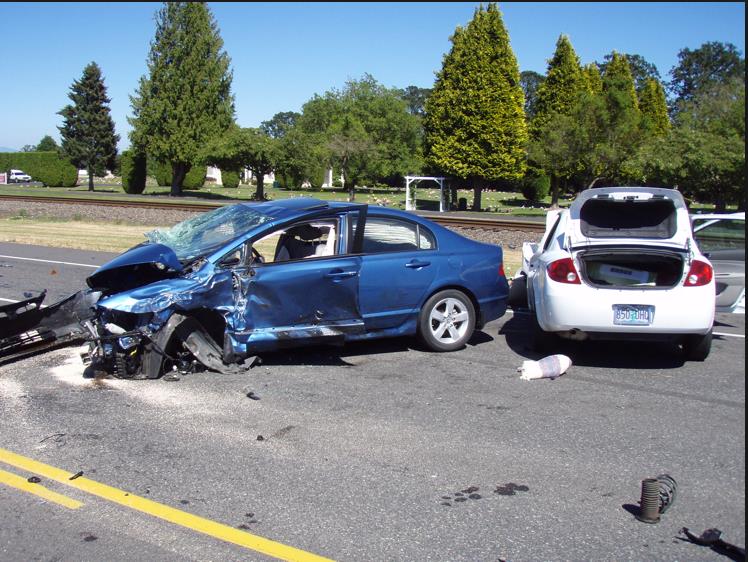 2 wrecked blue and white cars colliding on USA roadway.
